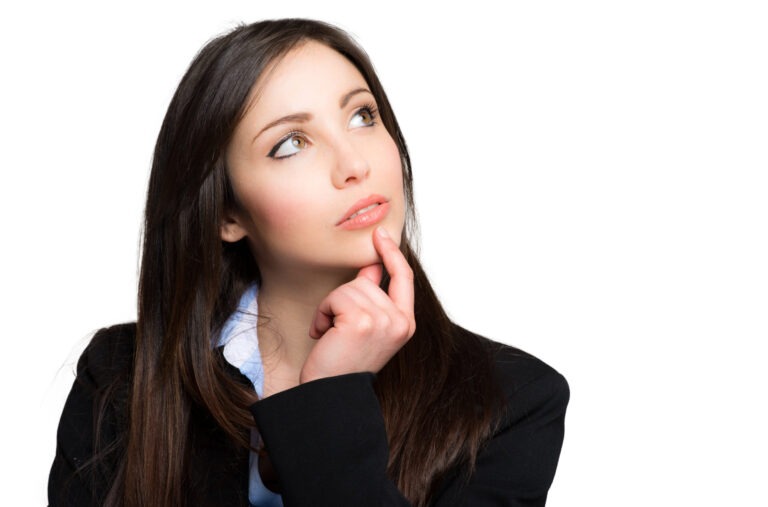 Businesswoman in a suit thoughtfully pondering, with her finger on her chin and a contemplative expression, against a white background.