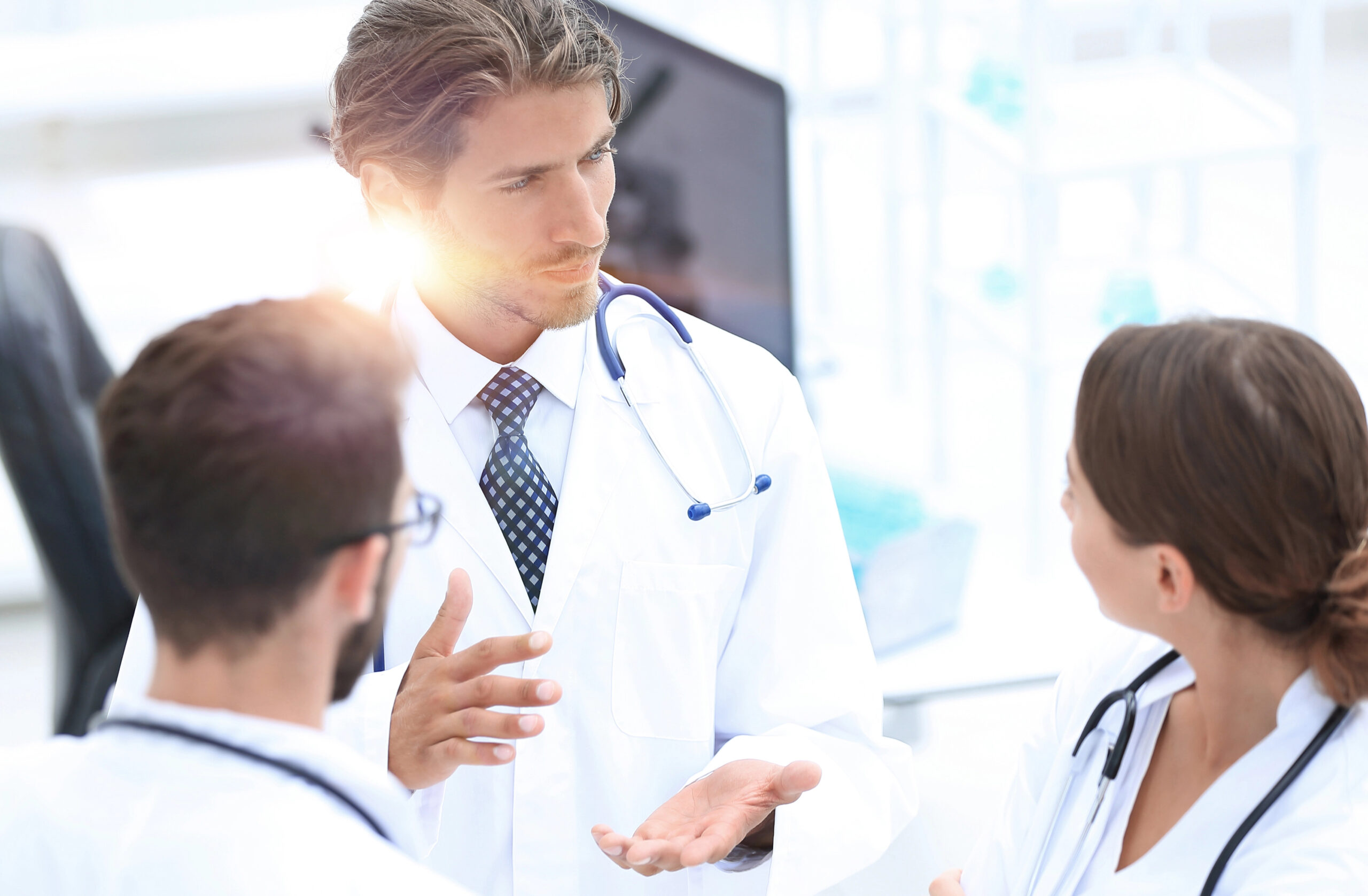 Healthcare professionals engage in a collaborative discussion, focusing on patient care. The setting highlights teamwork in a modern medical environment.