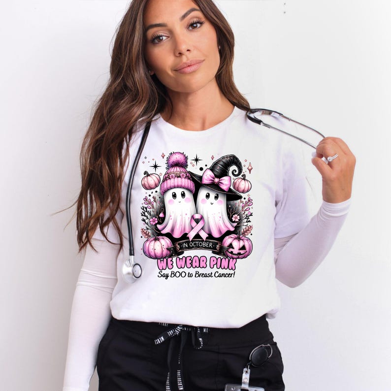 A woman in a white shirt featuring cartoon ghosts with pink accessories promotes breast cancer awareness for October. The design encourages wearing pink.